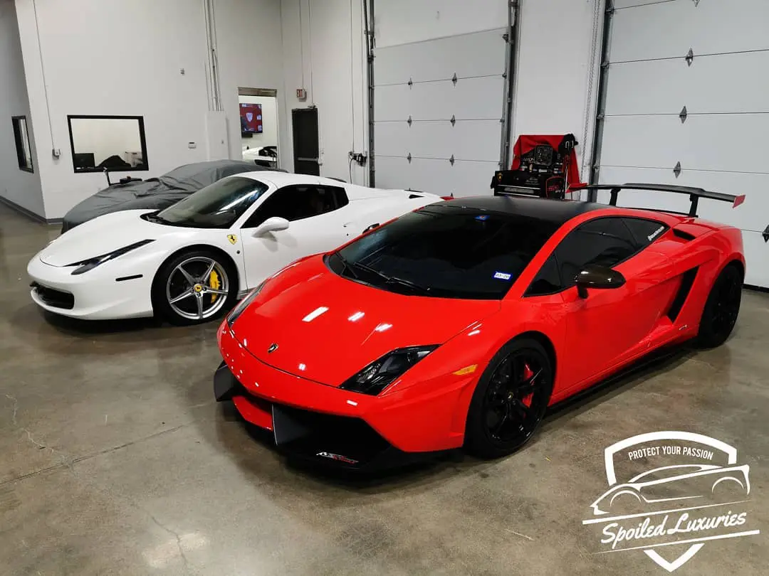 A red lamborghini parked in front of two other cars.