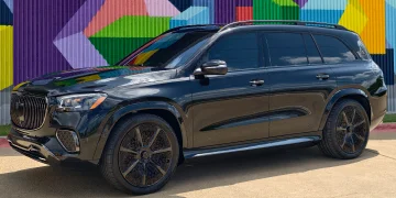 Glossy black Mercedes-Maybach SUV parked in front of a brightly colored geometric mural, featuring tinted windows, large black wheels, and a bold front grille.