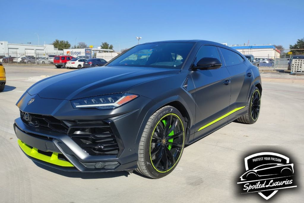 A matte black Lamborghini Urus with neon green accents is parked in a sunny lot, showcasing a flawless, customized finish likely protected by Paint Protection Film (PPF). This image highlights the visual and functional Paint Protection Film benefits, from aesthetic enhancement to long-term protection against Texas road and weather conditions.
