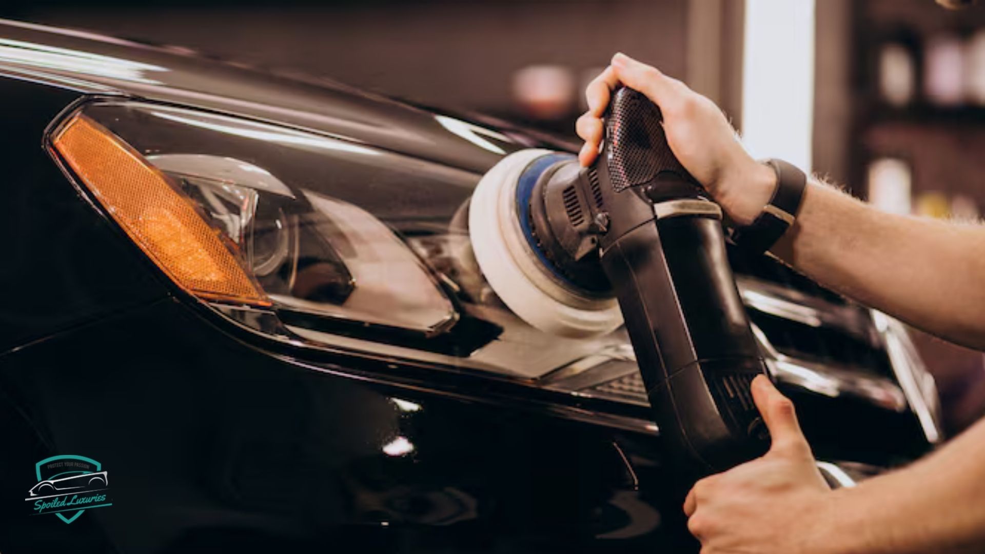 Hands holding a power buffer polishing the headlight of a black car, restoring clarity as part of exterior car detailing.