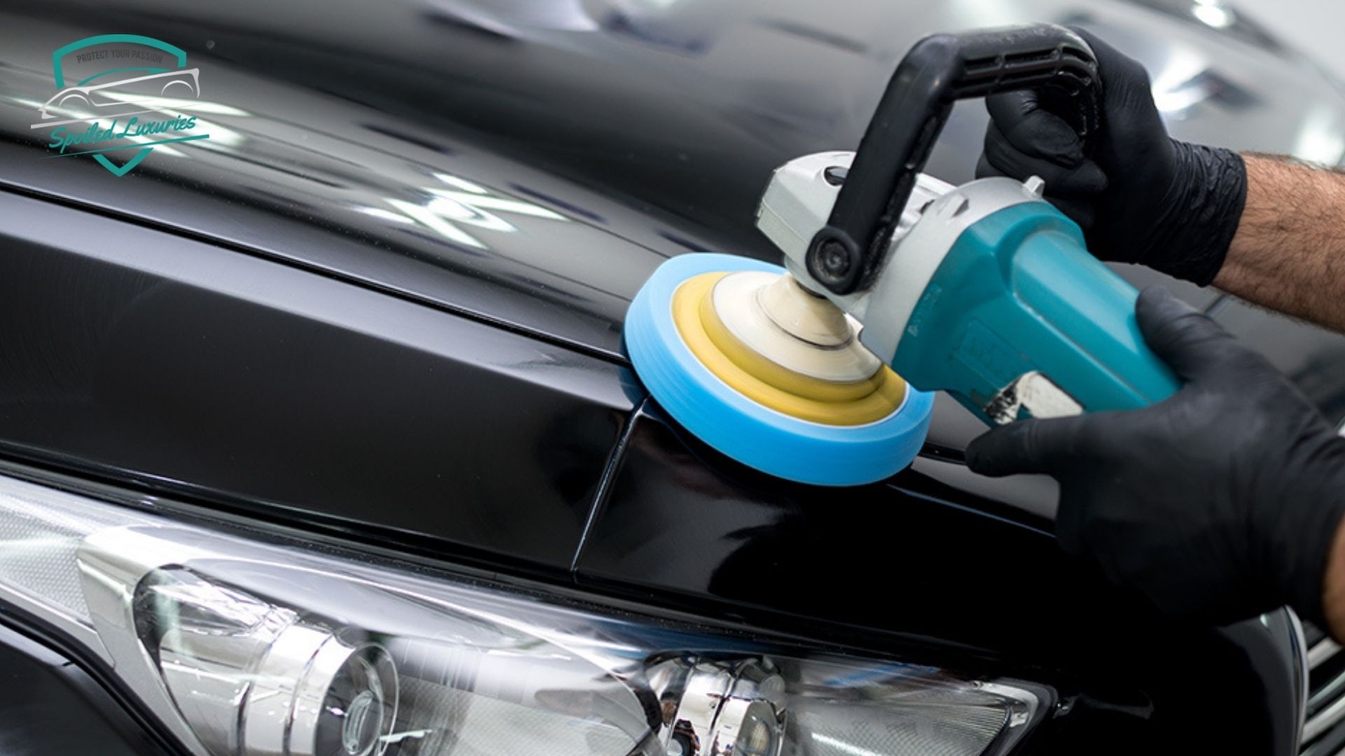 Technician using a machine polisher on a glossy black car hood during car detailing. The polishing pad buffs the paint to enhance shine and remove surface imperfections.